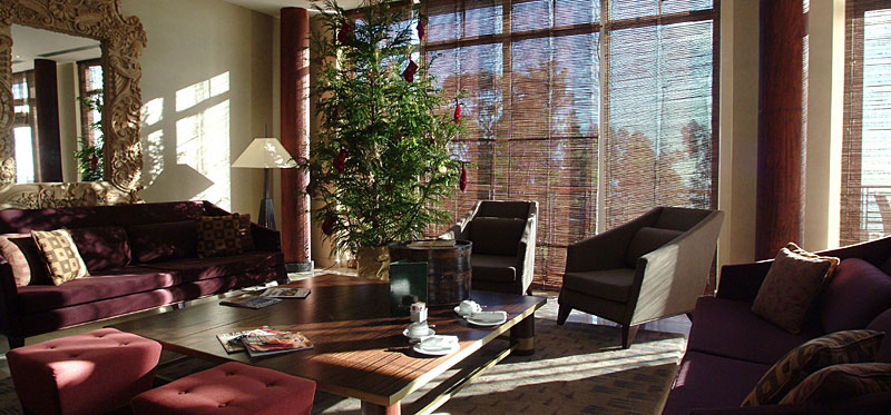 Lounge des Choupana Hills mit dunklem Holz, Bambusrollos und warmen Rottönen
